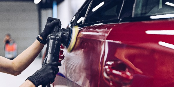 Man polishing car paint varnish in detailing studio