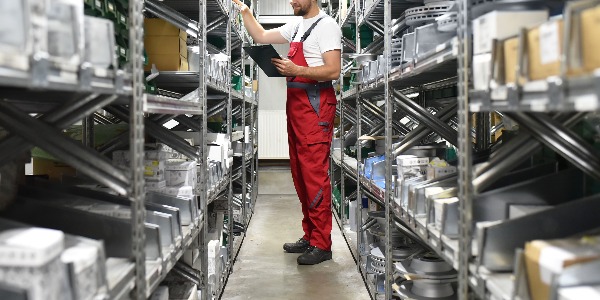 Mitarbeiter im Lager mit KFZ-Ersatzteilen in einer Autowerkstatt // Employees in the warehouse with spare parts for cars in a garage