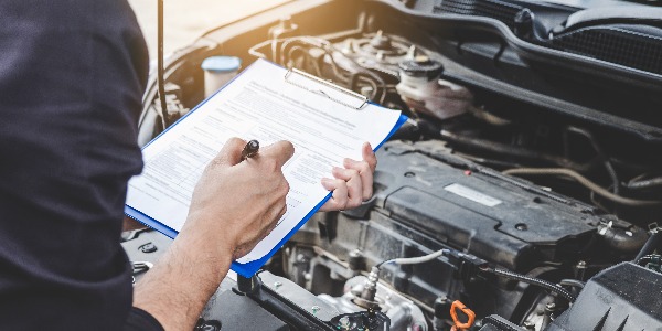 Services car engine machine concept, Automobile mechanic repairman checking a car engine with inspecting writing to the clipboard the checklist for repair machine, car service and maintenance